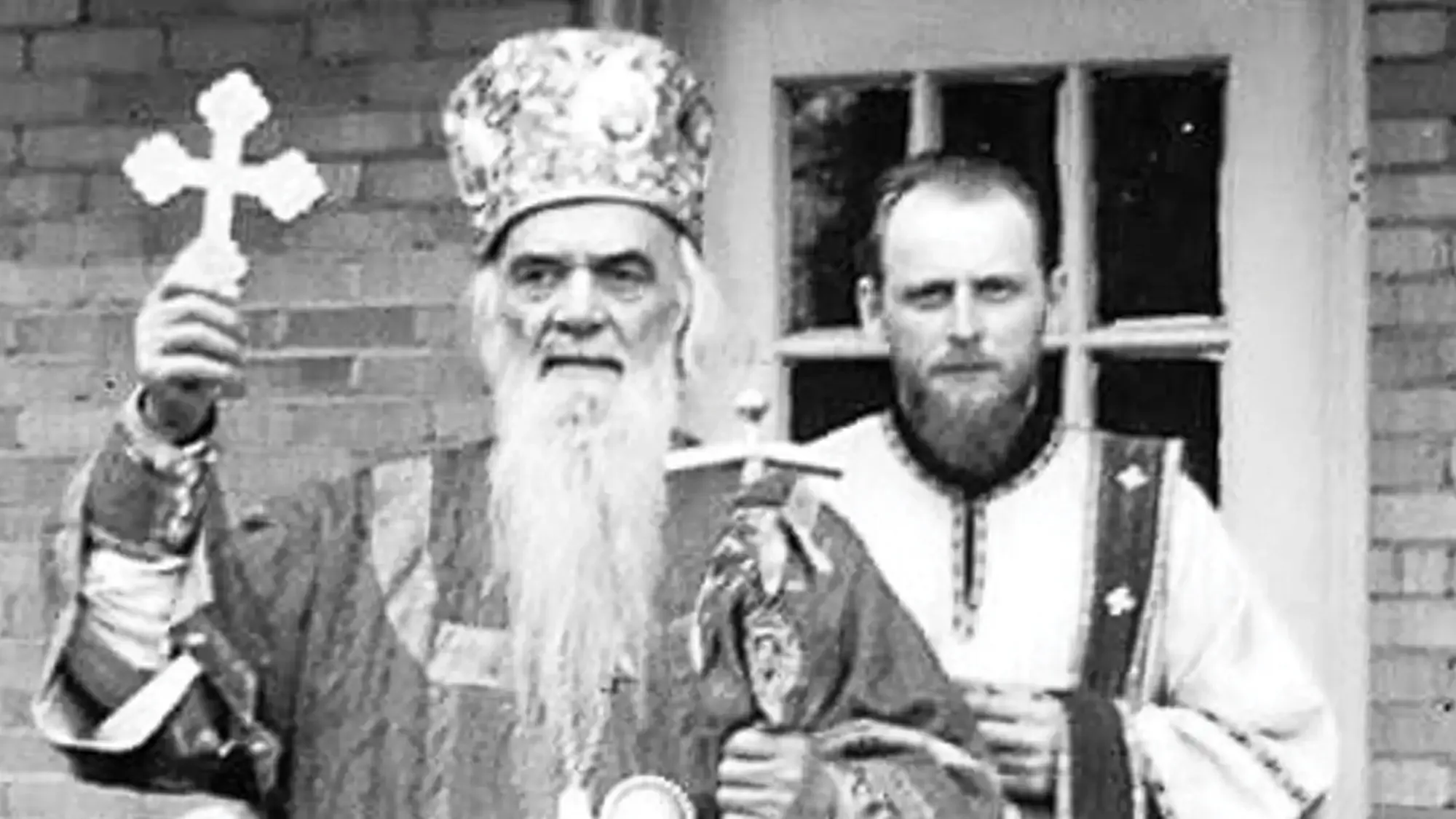 St. Nikolai Velimirovich stands outside St. Tikhon's Seminary holding a cross while vested.